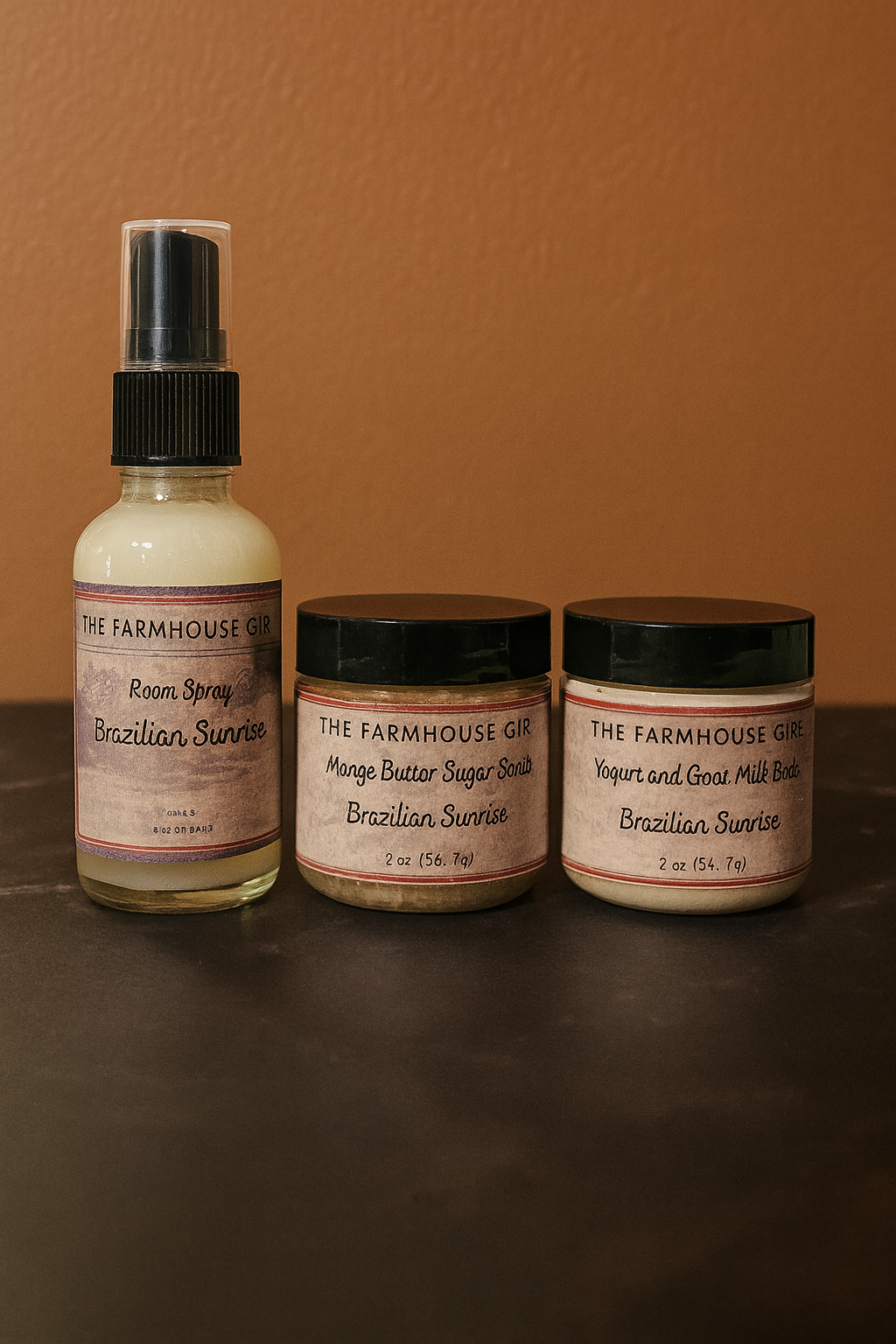 Three products from 'The Farmhouse Girl' on a brown surface with a brown background