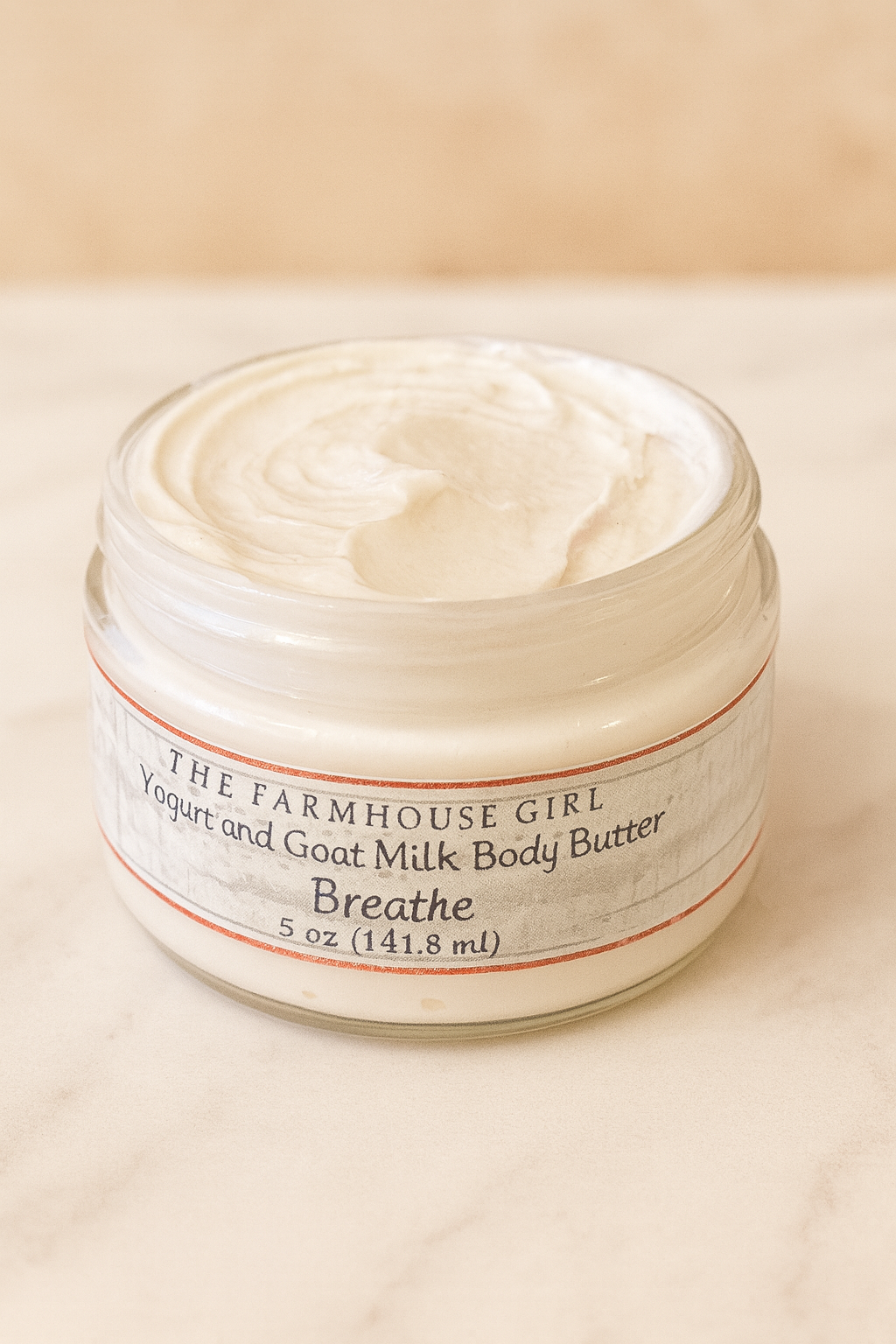 Jar of The Farmhouse Girl yogurt and goat milk body butter on a beige background