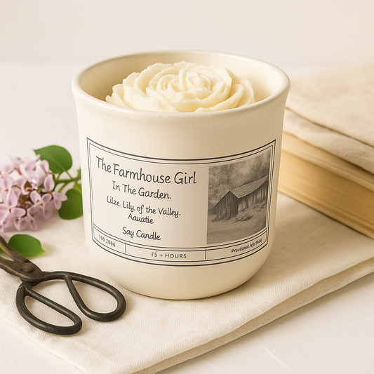 Candle with a label on a surface with a book and flowers
